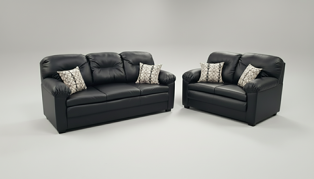 Black leather sofa set with patterned toss pillows on a gray background